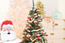 a Christmas tree with lights, colorful pompom garlands, a red pillow and a Santa one will add a fun and dreamy holiday feel