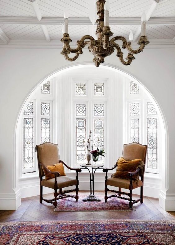 a beautiful alcove with a bay window with stained glass, a vintage table and carved chairs - this glass keeps privacy yet provides light