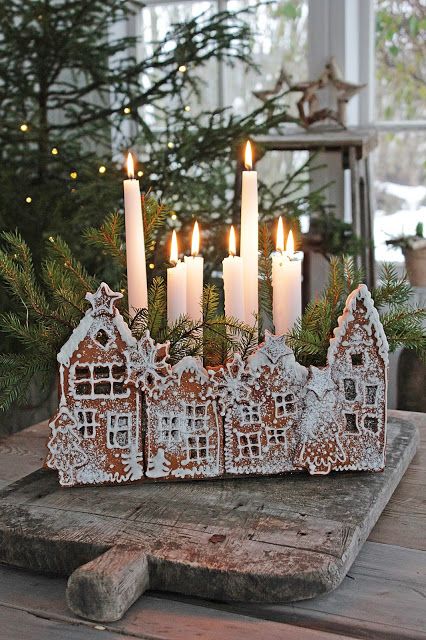 a creative candleholder of gingerbread houses with glazing and evergreens and tall and thin candles is amazing