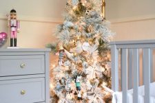 a flocked Christmas tree with lights and bvarious ornaments in a bucket to create a holiday feel in a farmhouse nursery