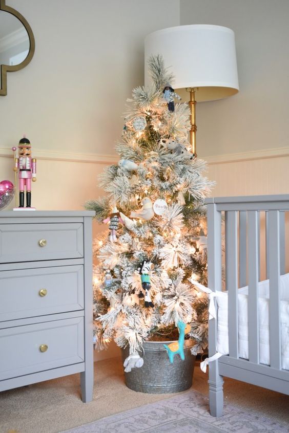 a flocked Christmas tree with lights and bvarious ornaments in a bucket to create a holiday feel in a farmhouse nursery