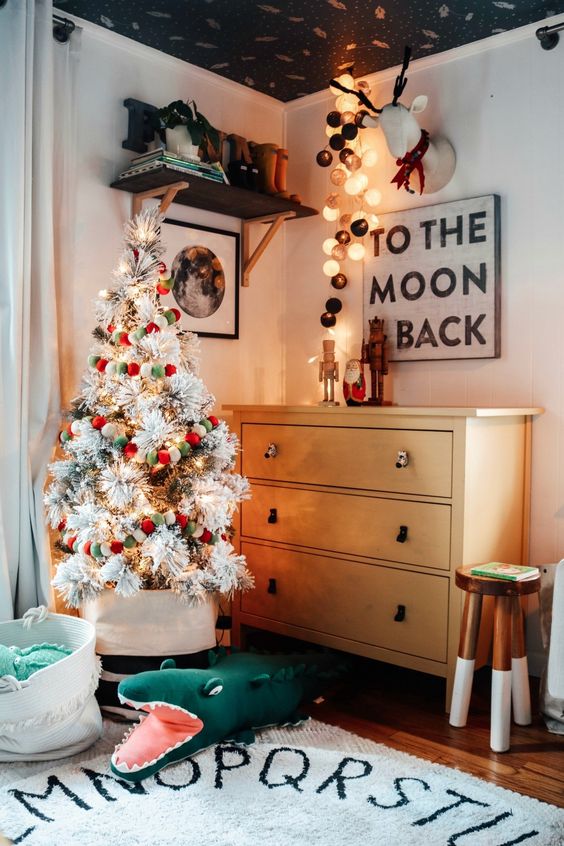 a flocked Christmas tree with lights and red, white and green pompom ornaments is a pretty and cool idea for holidays