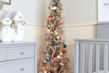 a metallic Christmas tree with lights, pretty ornaments and colorful pompom garlands is a lovely idea for any kids’ room
