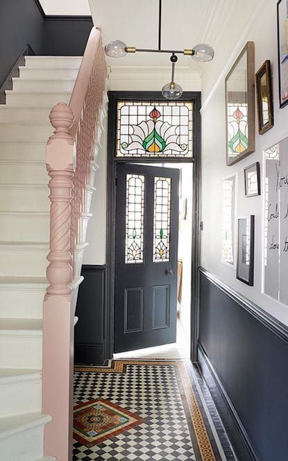 a small and cool entrance with a black door with stained glass, a gallery wall and a tiled floor looks amazing and very elegant