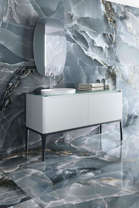 a sophisticated bathroom clad with grey onyx tiles looks jaw-dropping, a white vanity and a catchy mirror add to the space