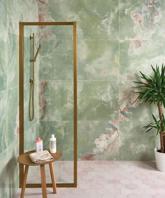 a stylish bathroom with green onyx tile walls, a hexagon tile floor, a wooden stool and a potted plant is a lovely space