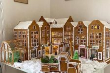 a super cool Christmas scene of cardboard gingerbread houses and a truck with Christmas trees, with lights and faux snow