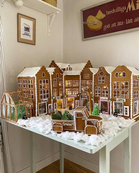 a super cool Christmas scene of cardboard gingerbread houses and a truck with Christmas trees, with lights and faux snow