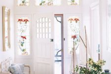 a vintage light-filled entryway with stained glass sidelights, a carved wooden bench and a table with decor