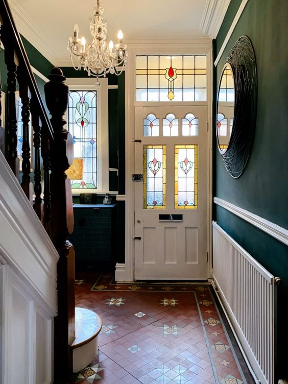 a vintage-styled entryway with tiles on the floor, dark green walls, a crystal chandelier and a stained glass window and foor is wow