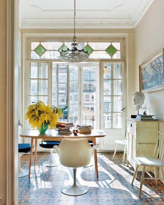 a welcoming home office with a large window with stained glass, cool modern furniture and a chic chandelier plus tiles on the floor