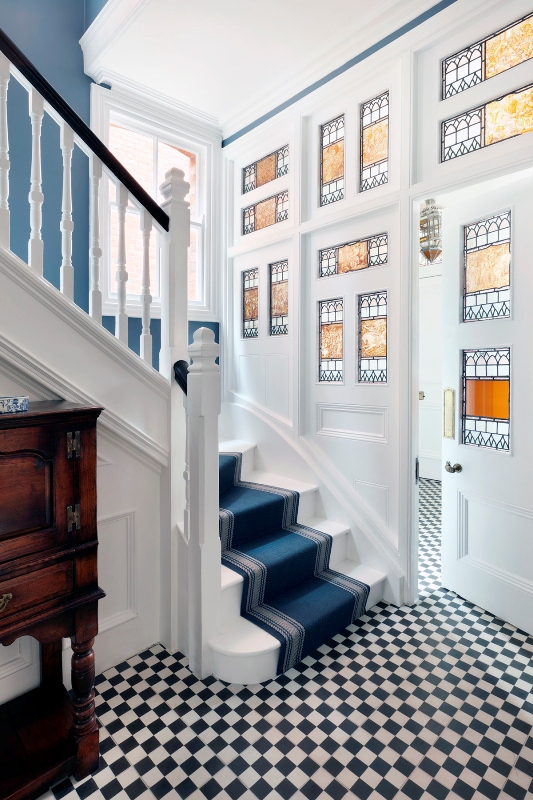 an entryway with stained glass sidelights and the door, blue walls and a checked black and white floor