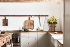 a chic contemporary kitchen in dove grey, with a wooden kitchen island and countertops and rough wooden beams