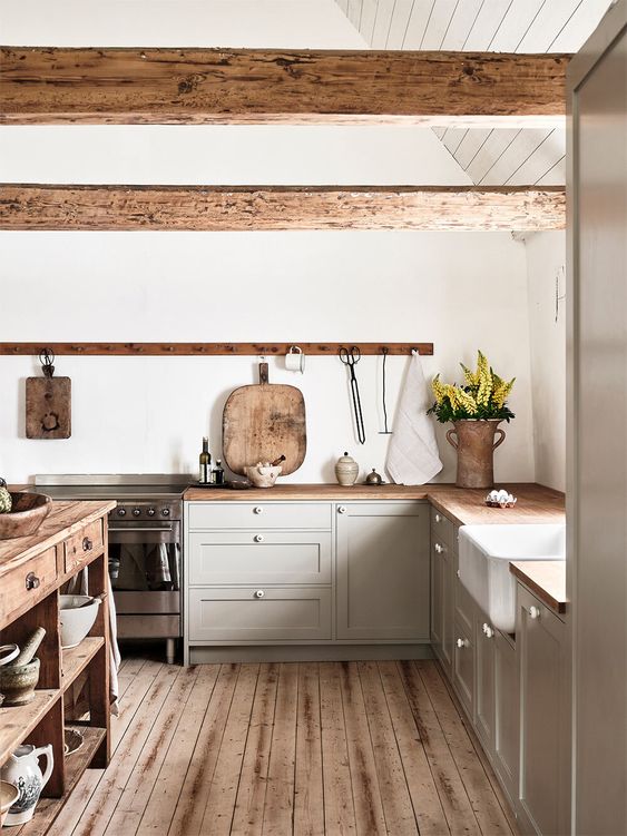 a chic contemporary kitchen in dove grey, with a wooden kitchen island and countertops and rough wooden beams