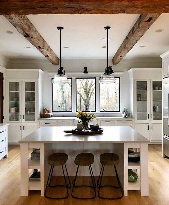 a clean white kitchen with rough wooden beams that add warmth and coziness to the space and make it catchy