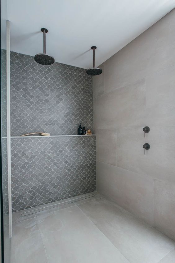 a concrete bathroom with an accent fish scale tile wall and dark brass fixtures is a pretty and cool space