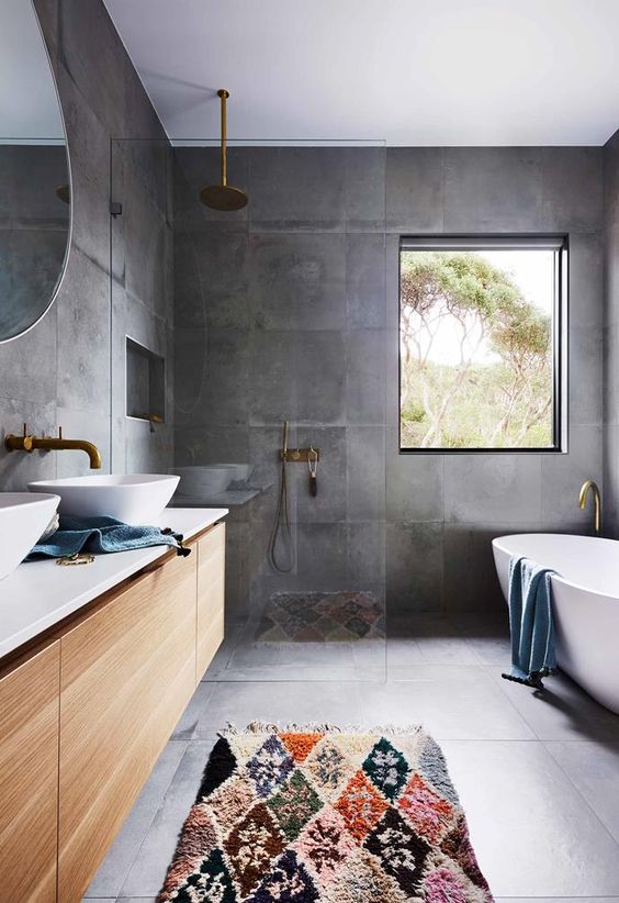 a contemporary bathroom with a concrete floor and walls, a floating vanity and brass fixtures plus an oval tub