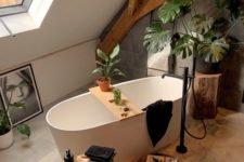 a contemporary bathroom with wooden beams, a grey tile wall, a bathtub, black textiles and candles