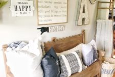 a cozy farmhouse entryway with a carved wooden bench, a gallery wall with signs and lamps, printed pillows and a blanket