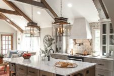 a dove grey vintage kitchen with a wooden kitchen island, printed tiles, wooden beams and refined lamps that accent the attic ceiling