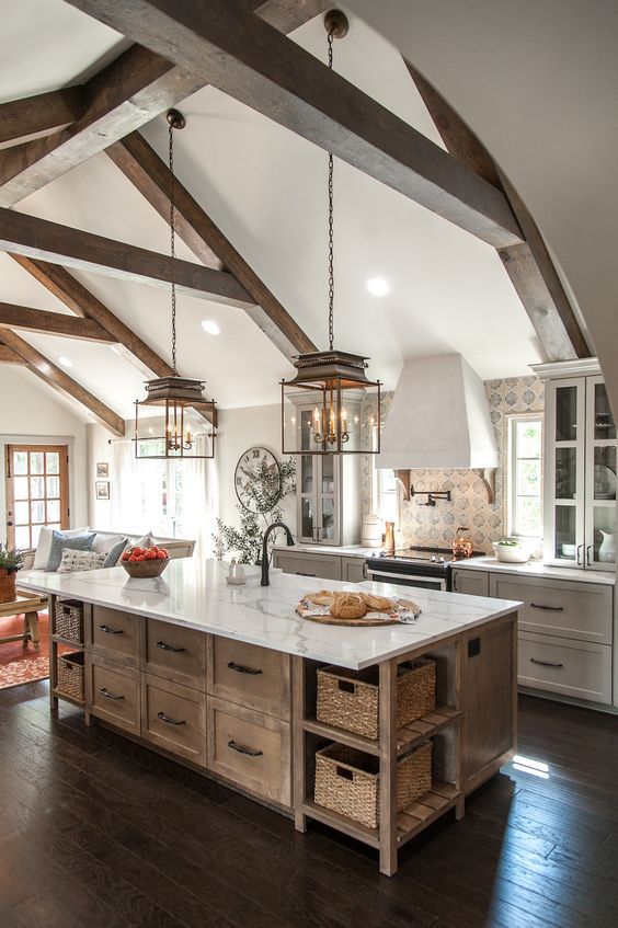 a dove grey vintage kitchen with a wooden kitchen island, printed tiles, wooden beams and refined lamps that accent the attic ceiling