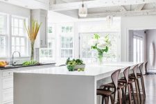 a light-filled kitchen with whitewashed wooden beams, skylights and a large kitchen island plus wooden stools