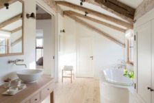 a neutral farmhouse bathroom with a large vanity, wooden beams on the ceiling, a large storage unit and a built-in tub