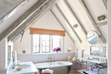 a neutral modern farmhouse bathroom with whitewashed wooden beams, a metal tub, two vanities and sinks