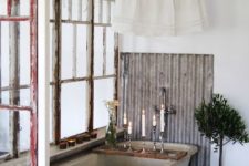 a vintage industrial bathroom with a concrete tub, shabby chic windows, some potted plants and candles