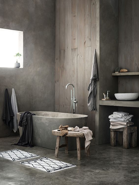 a wabi-sabi to Nordic bathroom with a concrete floor and walls, a concrete tub, a wooden wall and a built-in vanity plus a round sink