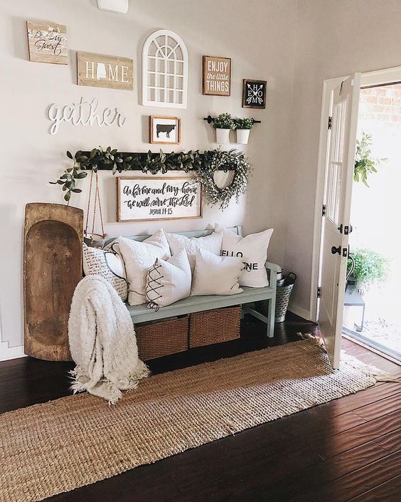 a welcoming entryway with a jute rug, a blue bench, printed pillows, a dough bowl and a large gallery wall with various pieces