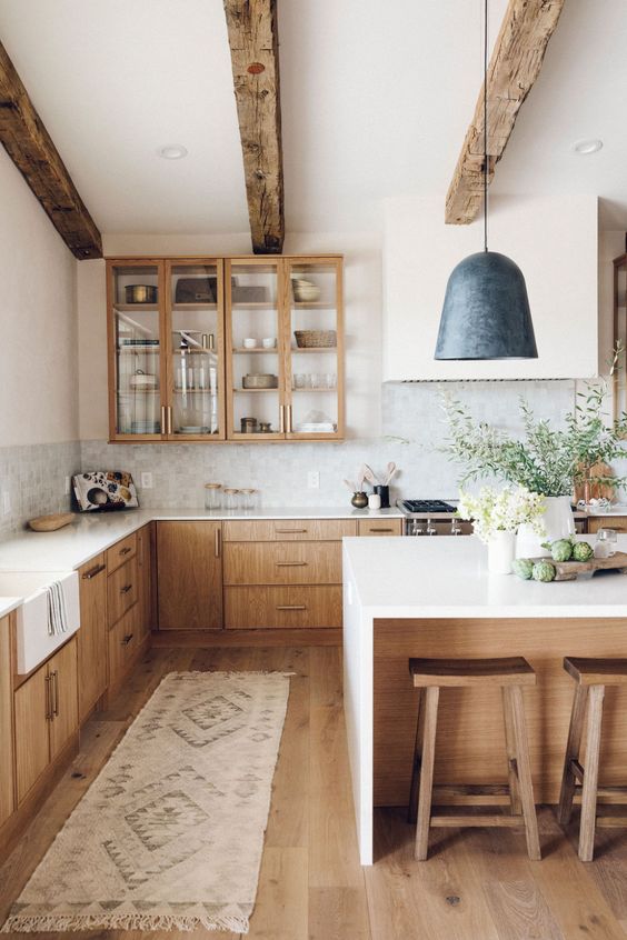 a welcoming modern farmhouse kitchen with light-colored cabinets, wooden beams and stools that warm up the space