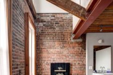 an industrial bathroom with brick walls, a shabby chic tub, wooden beams and a vintage sink