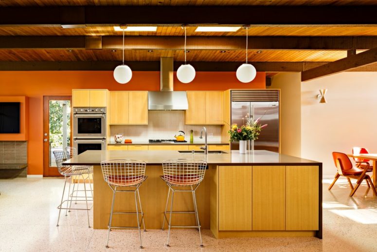 a yellow kitchen with a waterfall kitchen island with a dark countertop, metal chairs and pendant lamps  (risa boyer architecture)