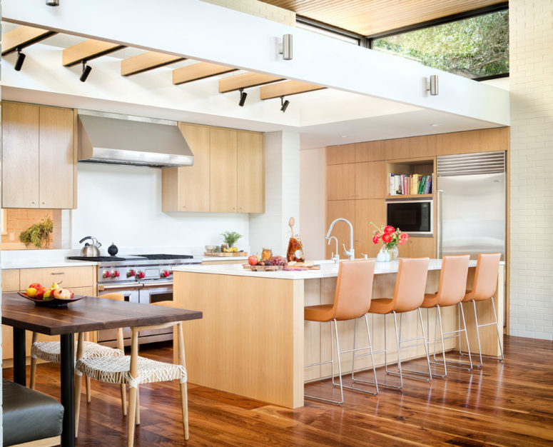 a lights-colored mid-century modern kitchen with white surfaces, orange stools and much light  (Allison Burke Interior Design)