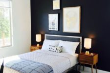a bold and dramatic mid-century modern bedroom with a blakc statement wall, a geometric rug, a black bed and rich-stained nightstands