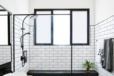 a bold monochromatic bathroom with white subway tiles and black hex ones, a floating vanity and bowl sinks plus black fixtures