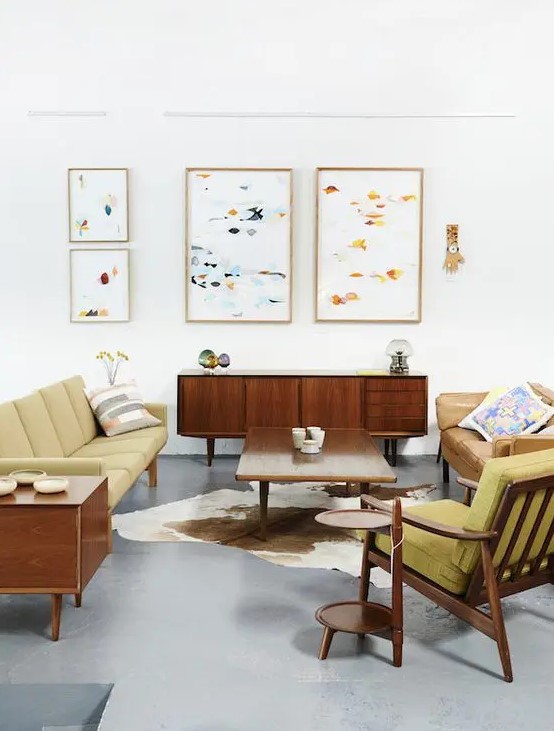 a bright mid-century modern living room with mustard colored furniture and abstract paintings