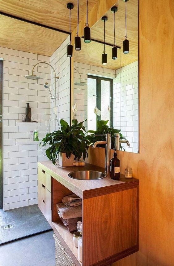 a chic mid-century modern space with white subway tiles, lots of plywood and wood, black pendant lamps over the sink