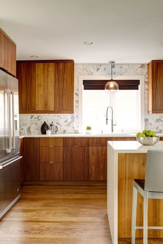 a contemporary meets mid-century modern kitchen with a marble tile backsplash, pendant lamps and a kitchen island with a waterfall top