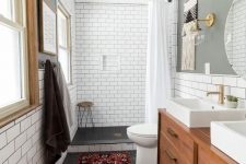 a cozy mid-century modern bathroom with white subway and black hex tiles, with a wooden vanity, a boho rug and windows