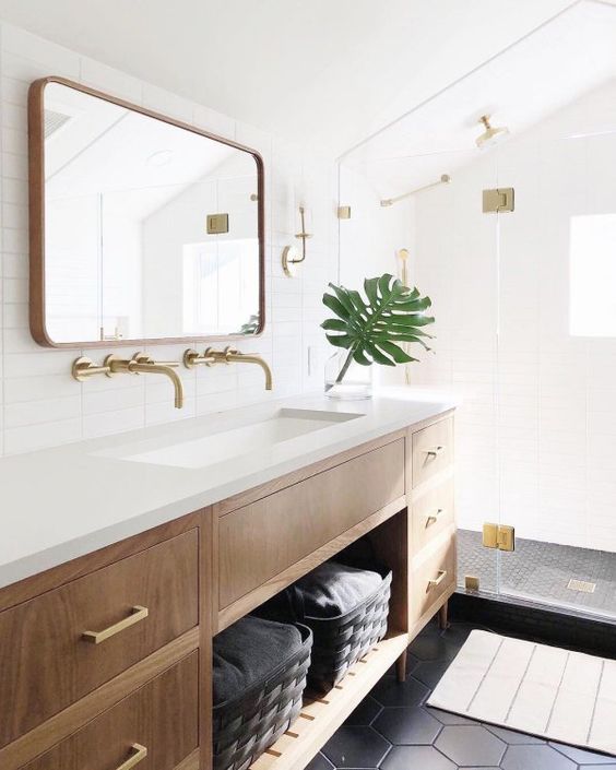 a gorgeous light-filled mid-century modern bathroom with windows, black hex tiles and skinny white ones, a wooden vanity and touches of gold