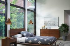 a light-filled mid-century modern bedroom with a glazed wall, rich stained wooden furniture, pendant lamps and a potted plant