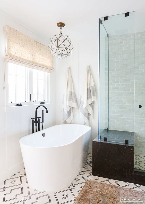 a mid-century modern bathroom with black and white mosaic tiles, a black stone clad shower and a 3D pendant lamp