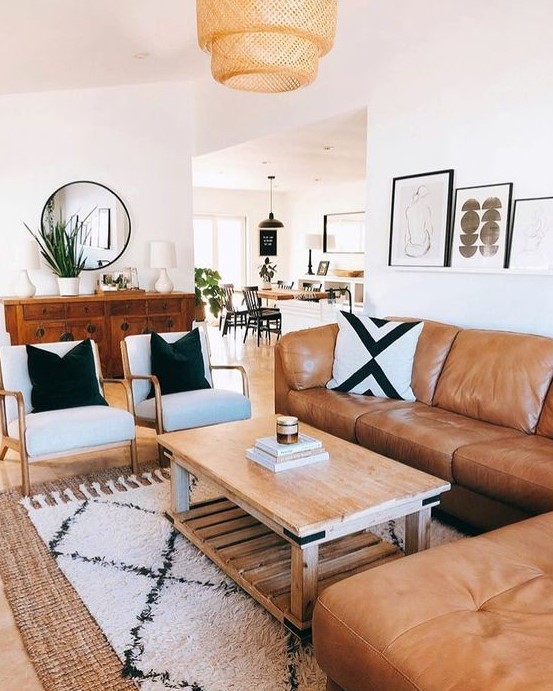 a mid-century modern living room with a boho feel, an amber leather sofa, neutral chairs, a wooden coffee table, printed textiles