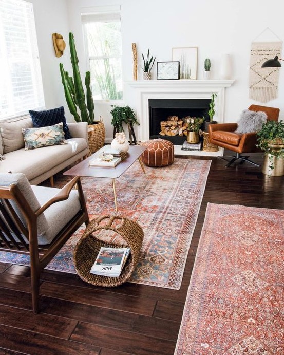 a mid-century modern living room with a non-working fireplace, a neutral sofa, an amber leather chair, baskets for storage and potted plants