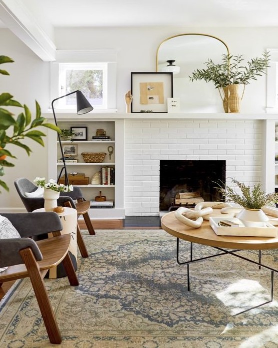 a mid-century modern living room with a non-working fireplace, plywood chairs, a large round table, built-in shelves