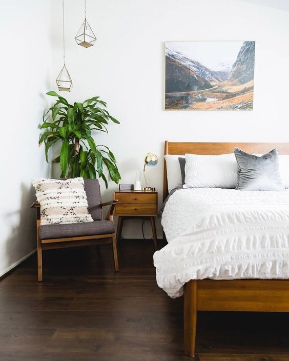 a mid-century modern meets boho bedroom with warm-colored wooden furniture, an artwork, pendant lamps and a potted plant