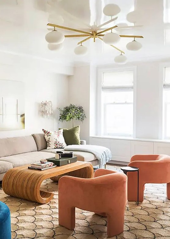 a neutral living room spruced up with bright furniture and decor, with orange curved chairs and a creative curved coffee table