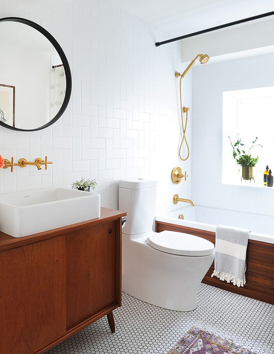 an elegant mid-century modern bathroom with white penny and subway tiles, rich stained furniture, black and gold touches